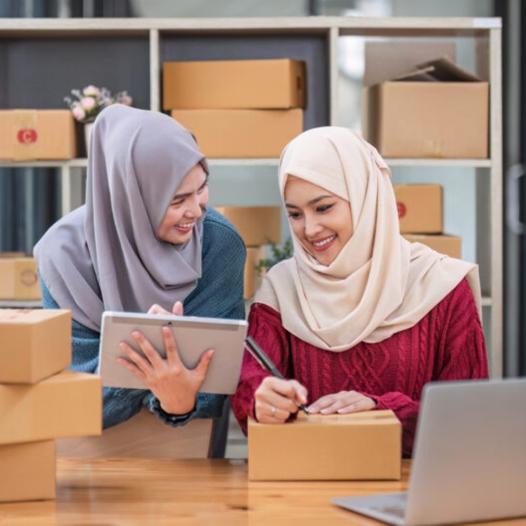 Friend muslim female work independent business sme online shopping working on laptop computer with parcel box on desk at home, SME online business and delivery concept..
